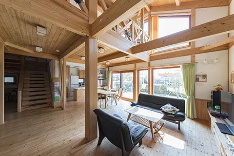 木の温もりを感じるリビングルーム。オレンジ色のソファと開放感のある空間。