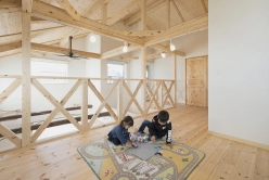 ロフトスペースで遊ぶ子供たち。木製の床と手すりがナチュラルな印象を与えている。