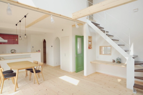 明るいリビングとダイニングが一体化した空間。白い壁と木製の階段が調和している。