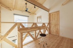 2階の木製ロフトスペース。窓から光が差し込み、作業机とスツールが置かれている。