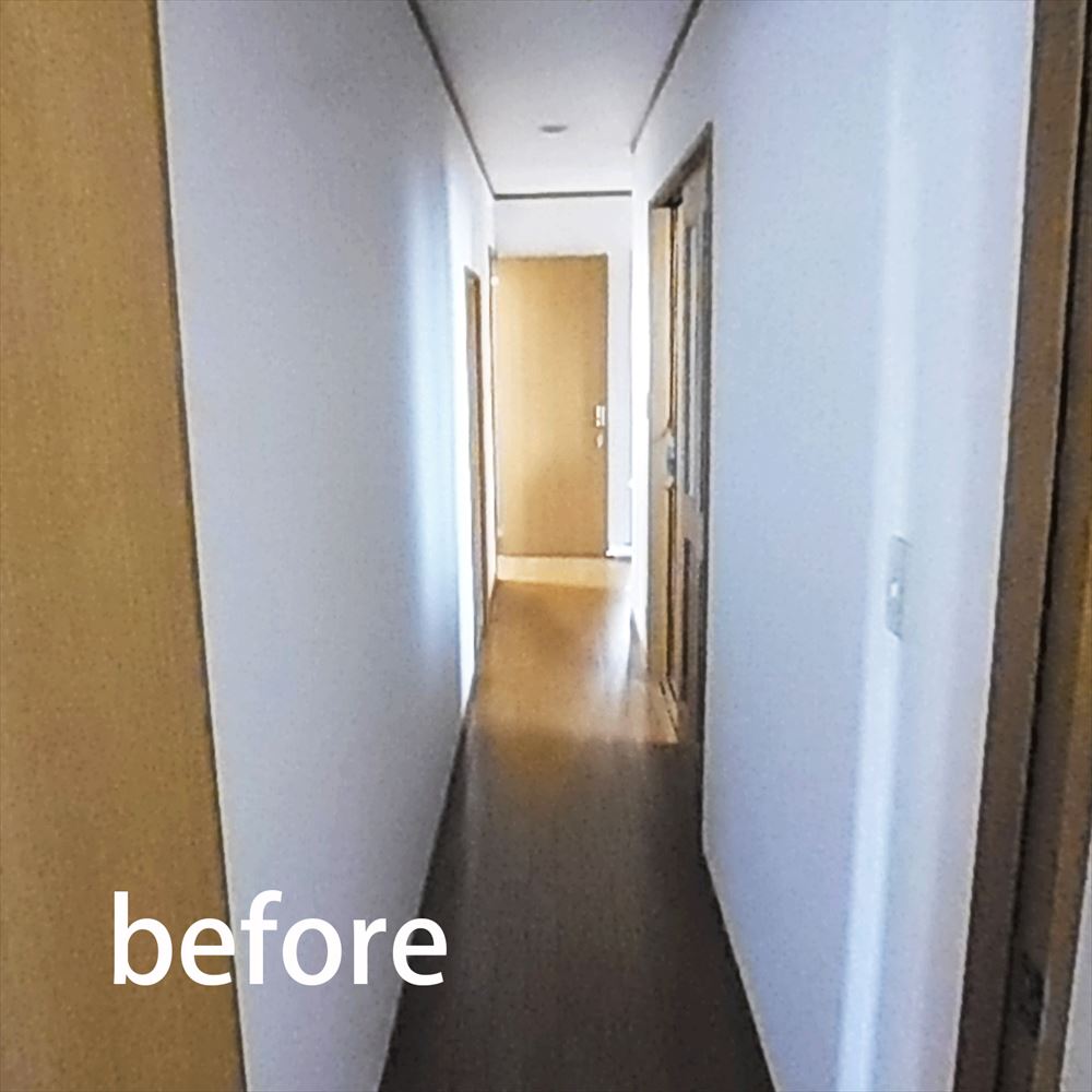 白い壁と木目調の床で構成された奥に玄関のドアが見える。